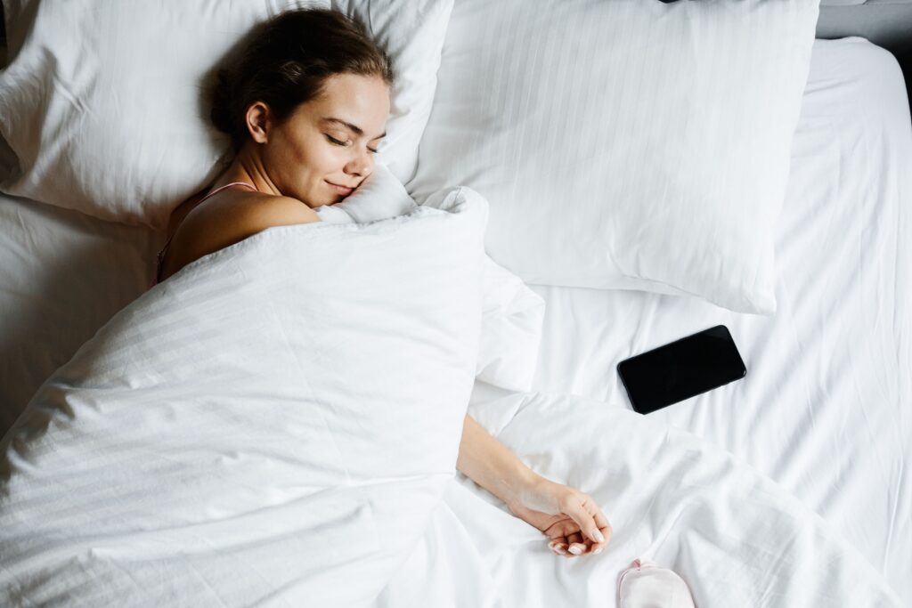 就寝中にベッドのそばへ置かれたスマートフォン